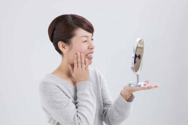 顎関節症を鏡でチェックする女性
